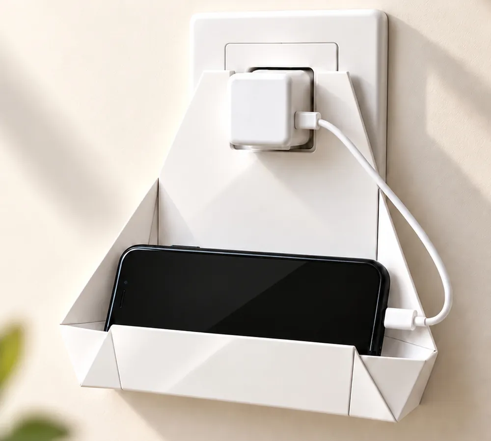 Suporte de papel modelo Dobra preso ao carregador na tomada, com um celular apoiado e carregando